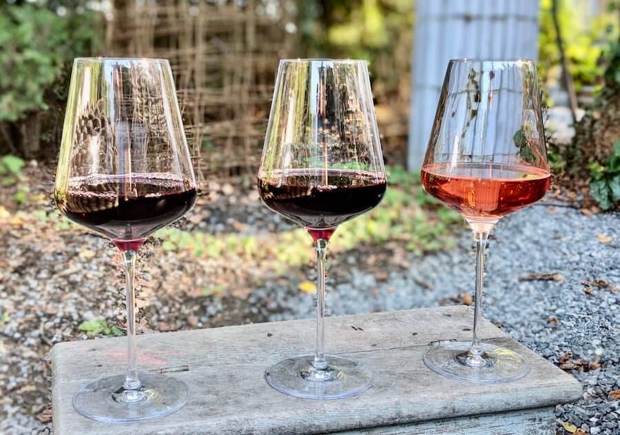 Three wine glasses sit on a wooden box outside at a romantic Long Island winery