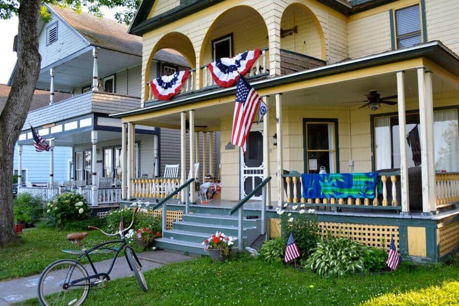 A Victorian-era house, displaying American flags, and a bicycle on the front lawn in Thousand Islands Village NY