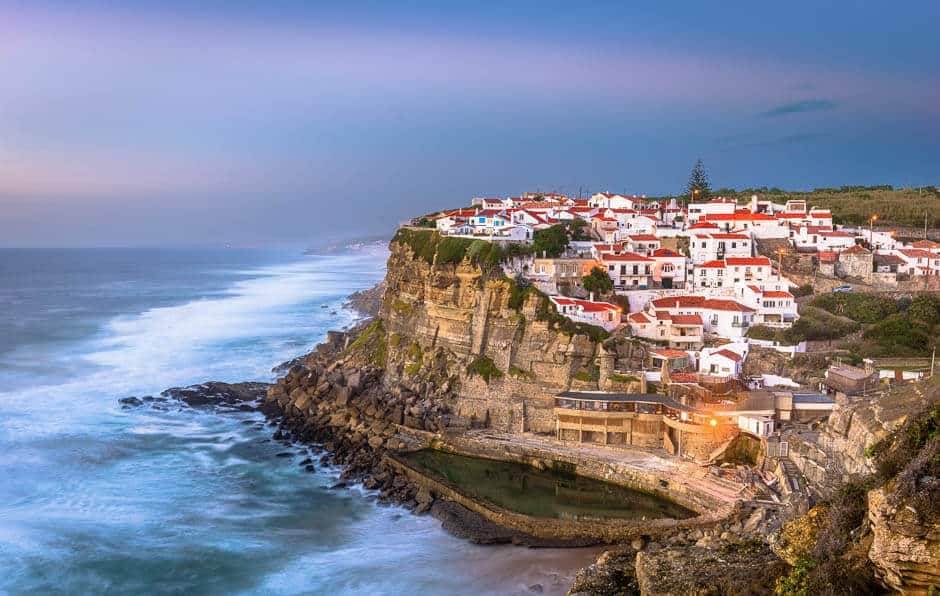 White washed houses with red roofs on a cliff by the Atlantic Ocean on the coast of Portugal
