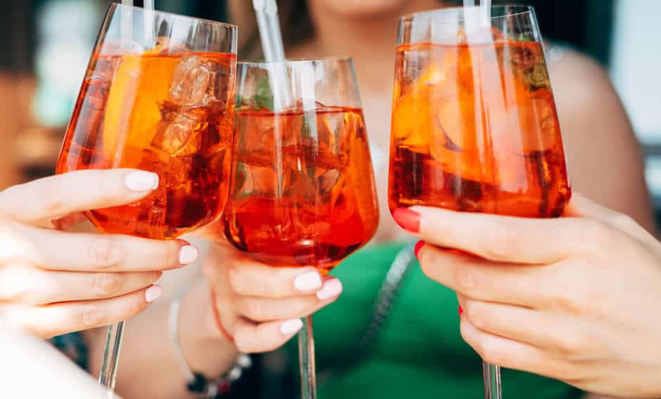 3 women toast with Aperol Spritz drinks