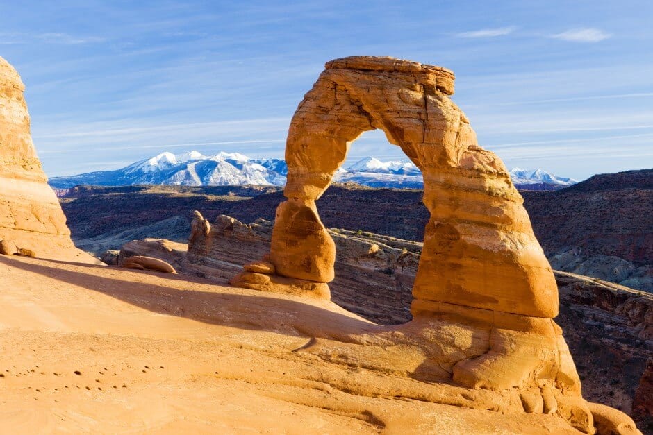 Impressive natural sandstone arch in front of snow-capped mountains in Arches National Park, Utah