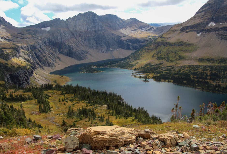 Elevated view down to a lake surrounded by exposed mountains in Glacier National Park, Montana
