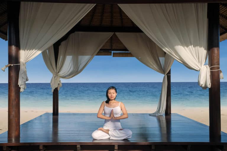 Woman in Lotus Position under a Canopy at the Beach as in movies like Eat Pray Love